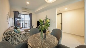 Una sala de estar moderna con una mesa redonda de mármol, sofás grises y un ventanal con cortinas.