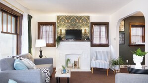 A living room with a fireplace, two sofas, a television, and a small table with a lamp. - Renovated 3BR Family Retreat, Sleeps 8 - Dog-Friendly (Akron)