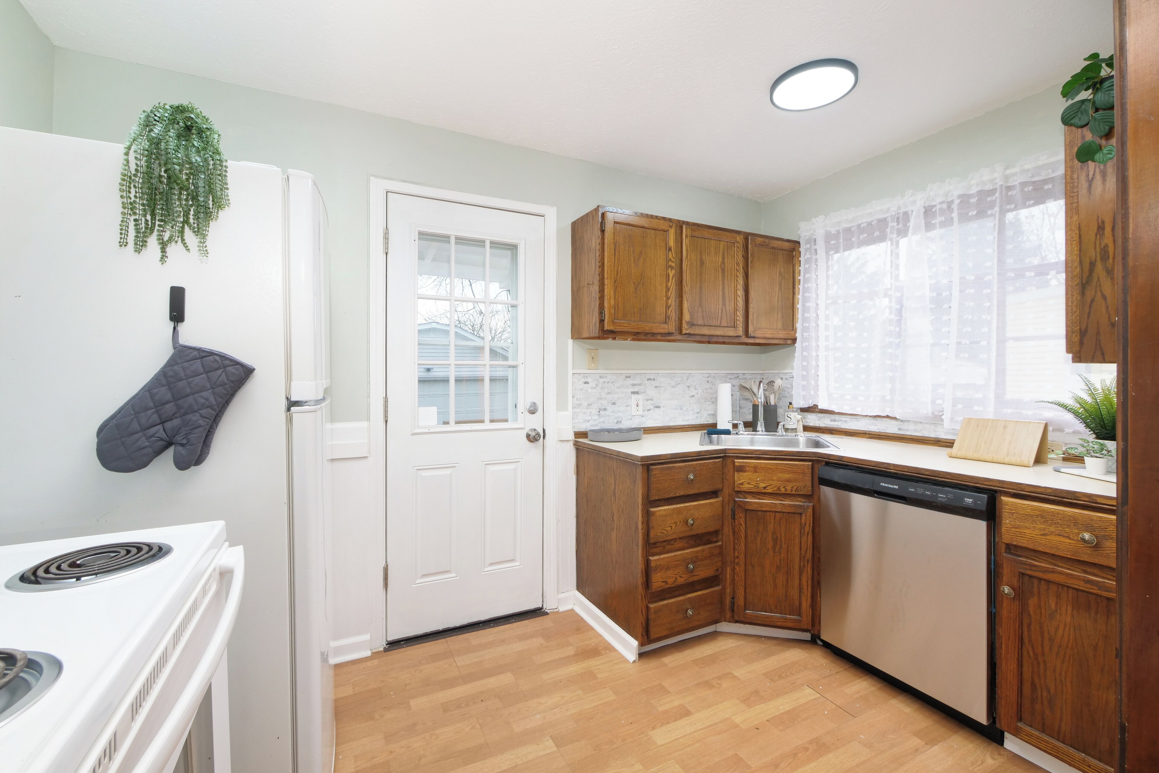 A kitchen with wooden cabinets, a white stove, and a dishwasher.