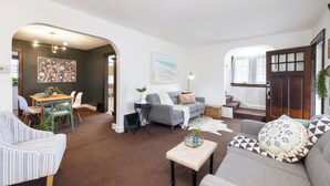 A spacious living area with a grey sofa, a blue armchair, and a dining table with chairs. - Renovated 3BR Family Retreat, Sleeps 8 - Dog-Friendly (Akron)
