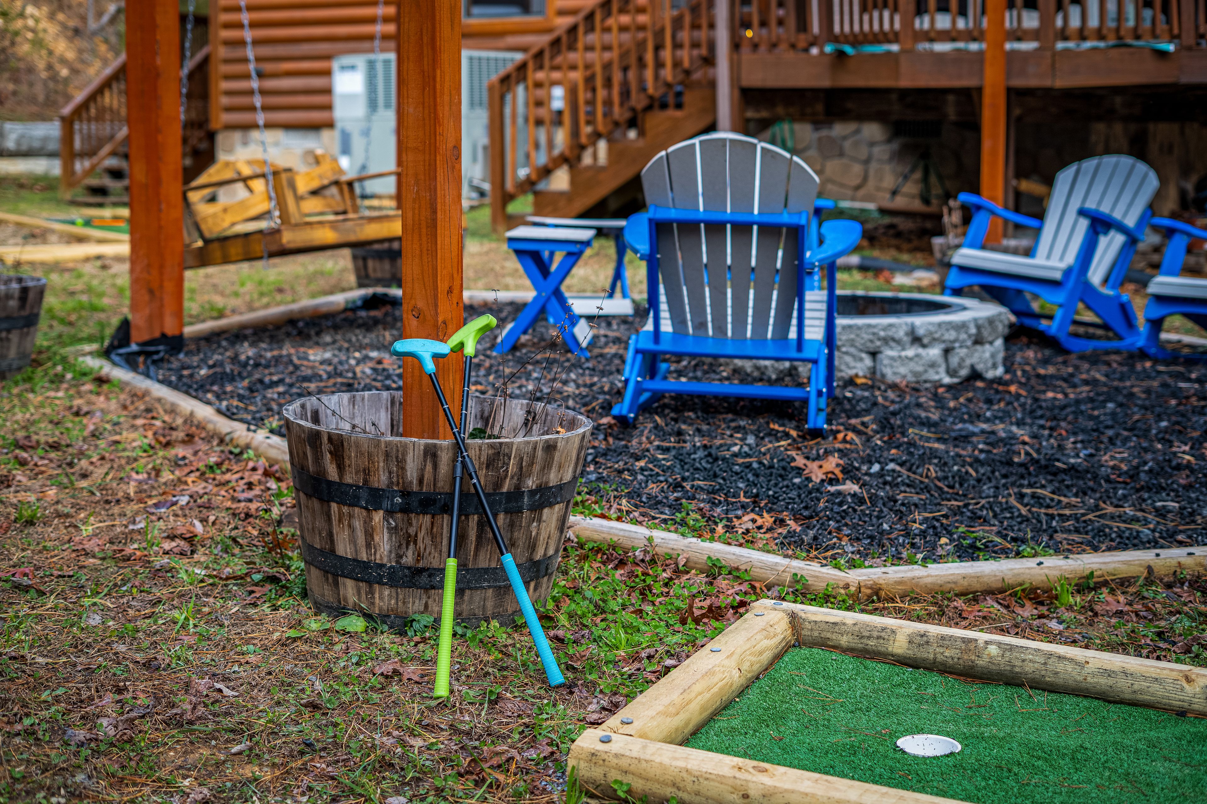 Une terrasse en bois avec des fauteuils Adirondack, un foyer et une petite table.