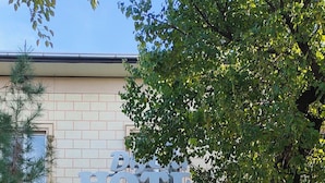 A hotel entrance with a brick facade, a sign above the door, and a tiled walkway leading to it.