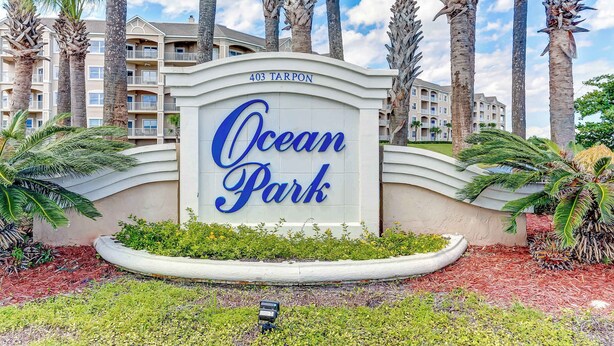 A sign for Ocean Park with a building in the background.