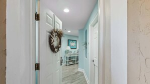 A hallway with light blue walls, white doors, and a white console table with decorative items.