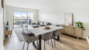 Una sala de estar moderna con una mesa de comedor, sofá y vistas al exterior.