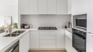 Una cocina moderna con armarios blancos, estufa a gas, horno integrado y lavavajillas.