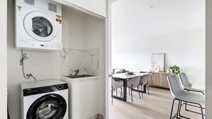 Una cocina moderna con lavadora y secadora integradas, salpicadero de mármol y comedor con mesa y sillas.
