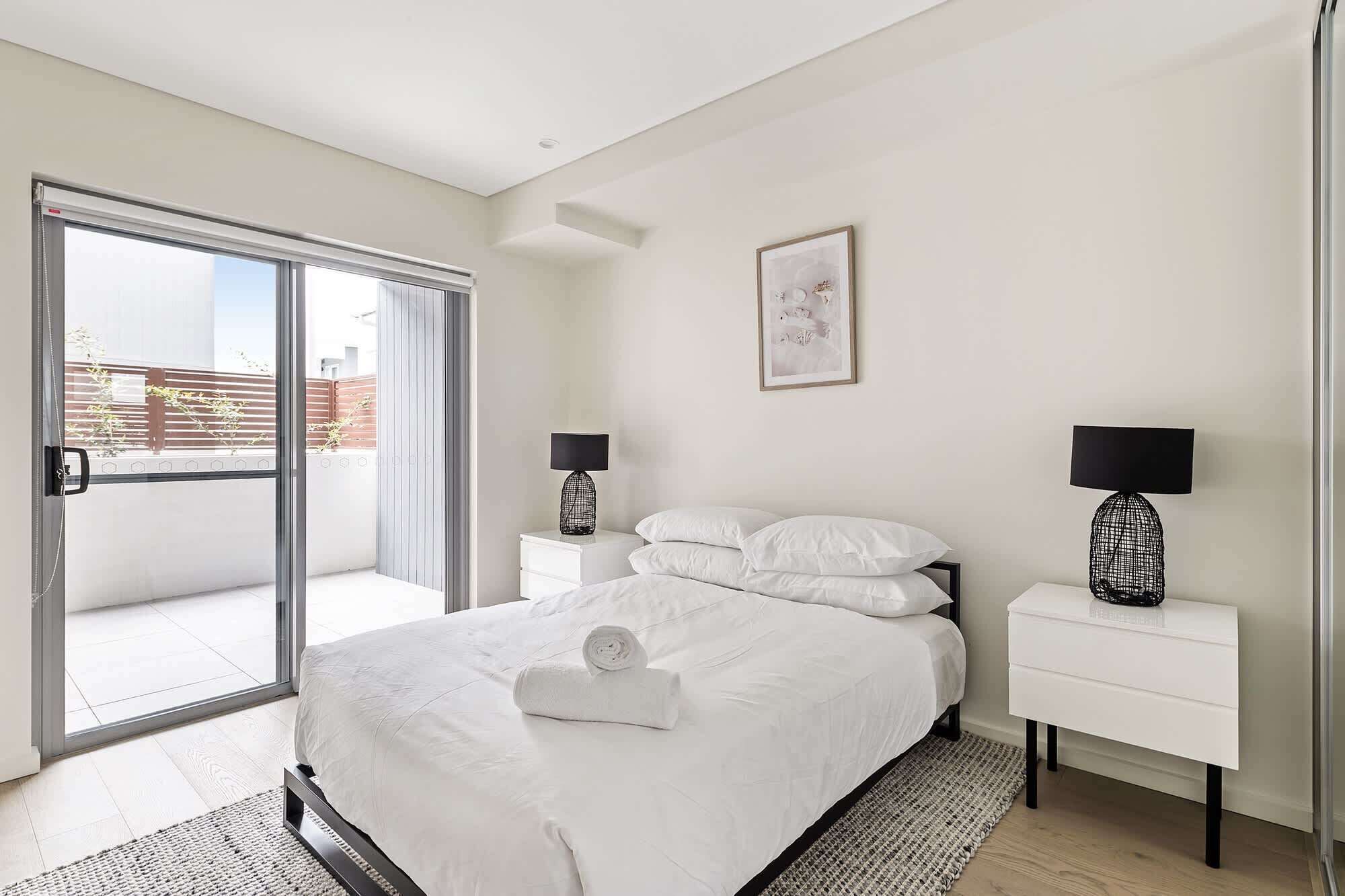 Une chambre à coucher avec un lit, deux tables de chevet, une fenêtre et une porte.