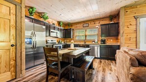 L’intérieur d’un chalet en bois comprend une cuisine, une table à manger et un banc.
