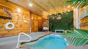 Un intérieur en bois avec une piscine, un fauteuil suspendu et un panneau indiquant l’emplacement d’un bar.