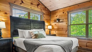 Une chambre dans une cabane en bois, avec un lit, des tables de chevet et des fenêtres.