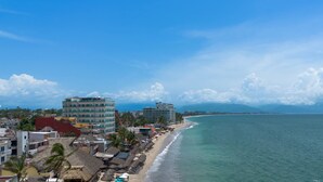 A coastal cityscape with a beach, buildings, and a clear sky.