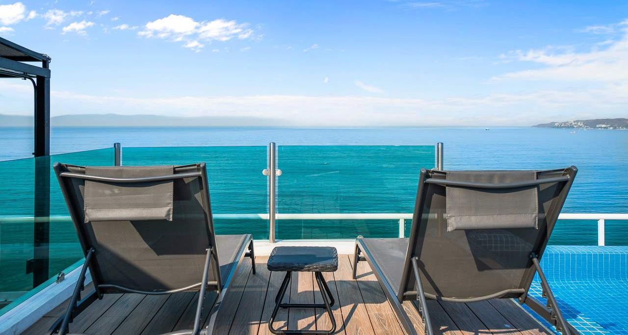 Une terrasse avec deux chaises et une petite table donnant sur un plan d’eau.