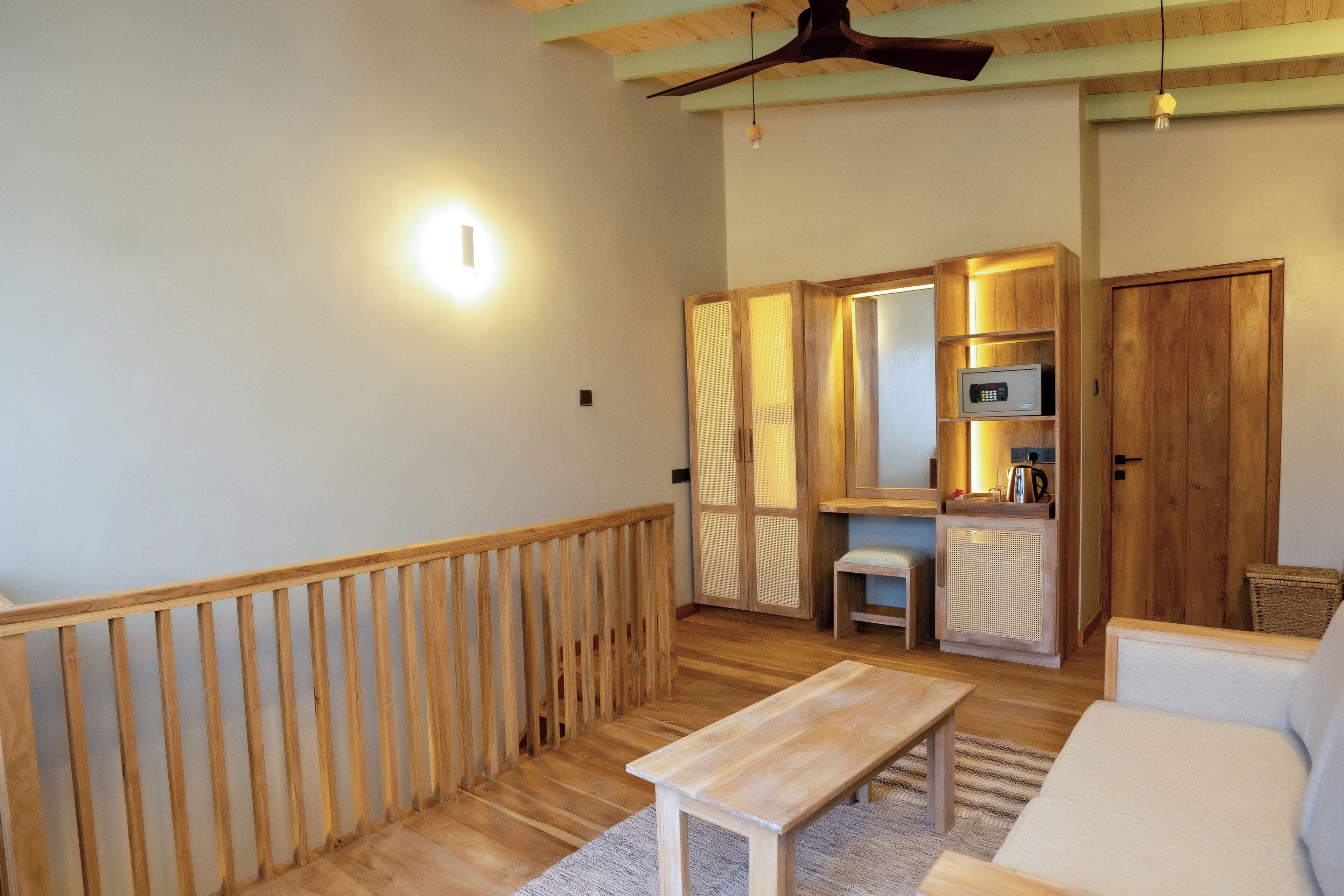 Una habitación acogedora con un banco de madera, un sofá, una mesita y una kitchenette con microondas y hervidor.