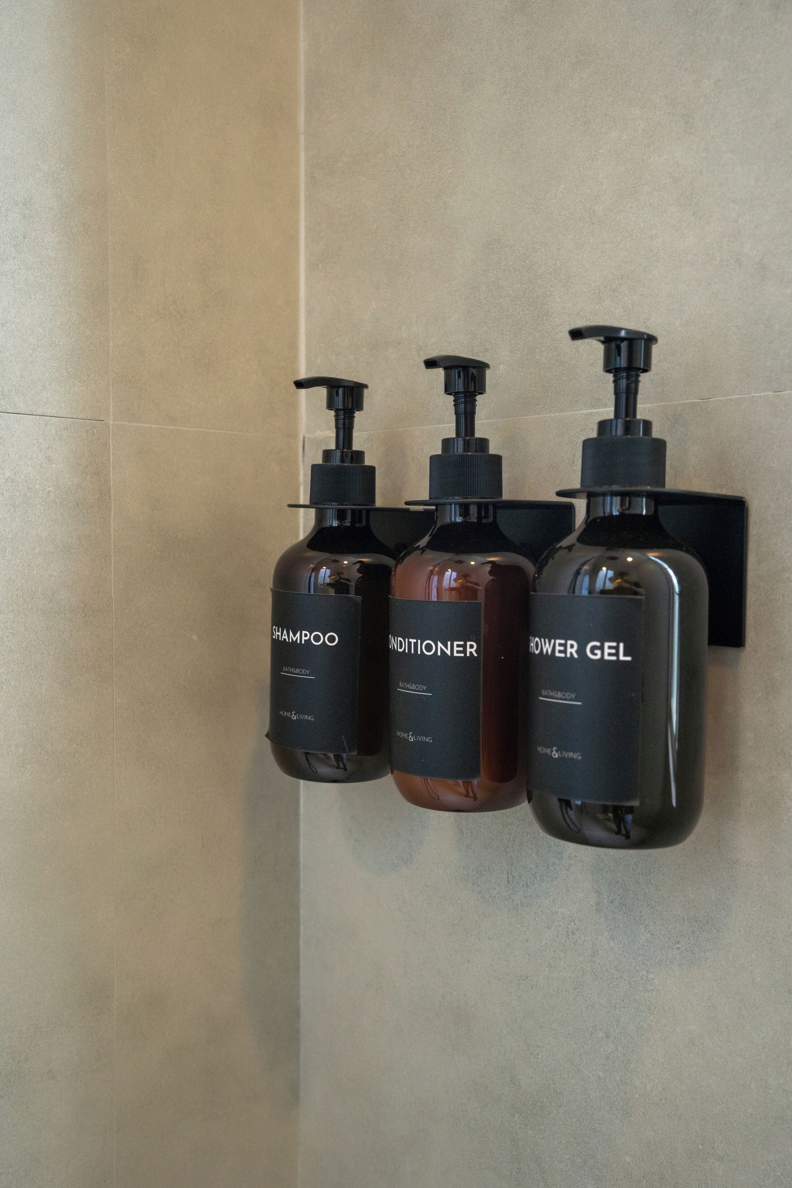 Three bottles of toiletries mounted on a wall.