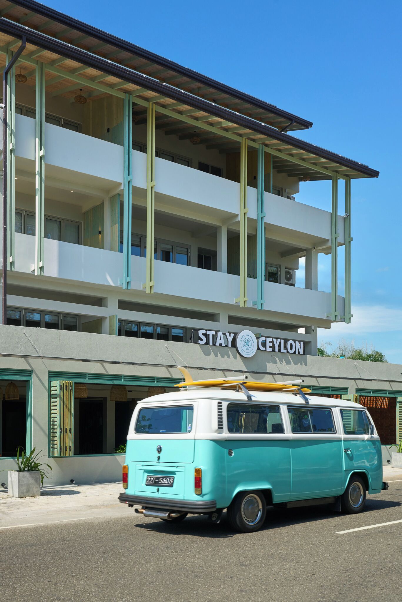A turquoise and white van parked in front of a building with a sign that reads "STAY CEYLON".