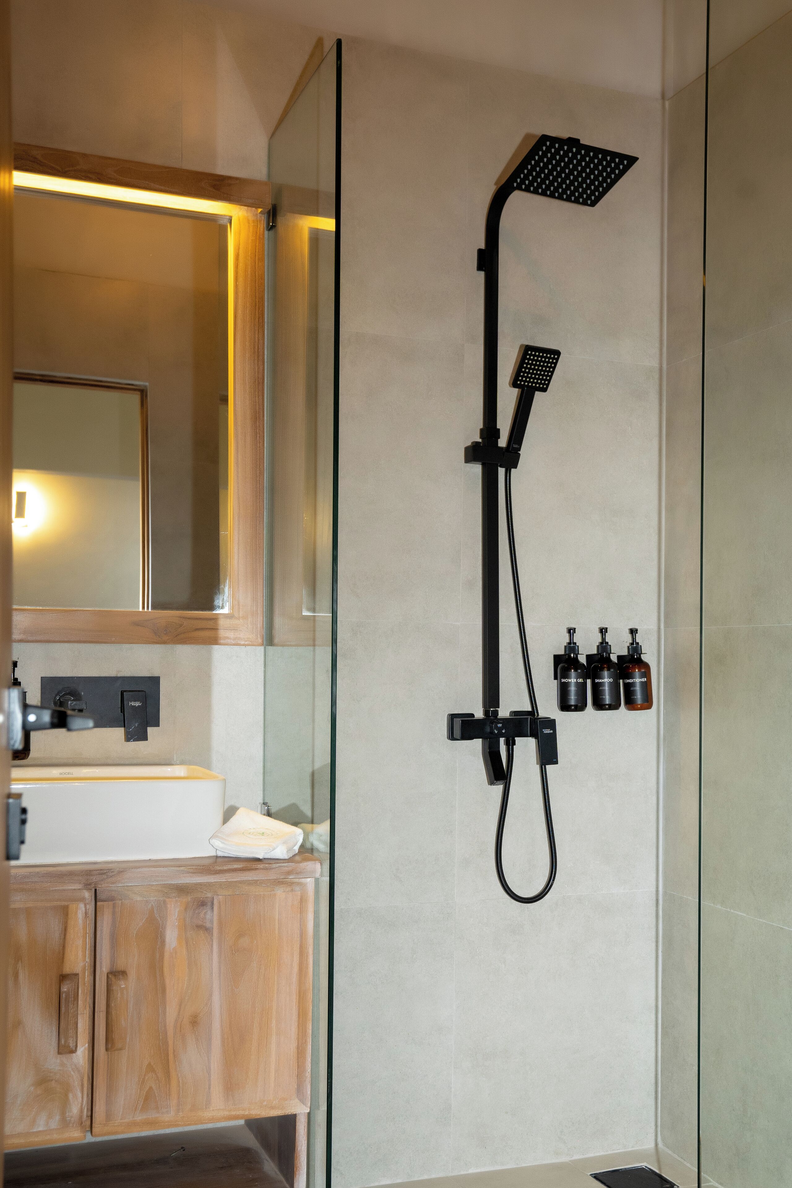 A modern bathroom with a glass shower enclosure, a wooden vanity, and a mirror above the sink.