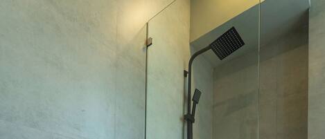 A modern bathroom with a toilet, a glass-enclosed shower, and a visible toilet paper holder.