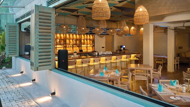 A restaurant with outdoor seating, wicker hanging lights, and a bar area with a counter and stools. - Stay Ceylon - Weligama (Weligama)
