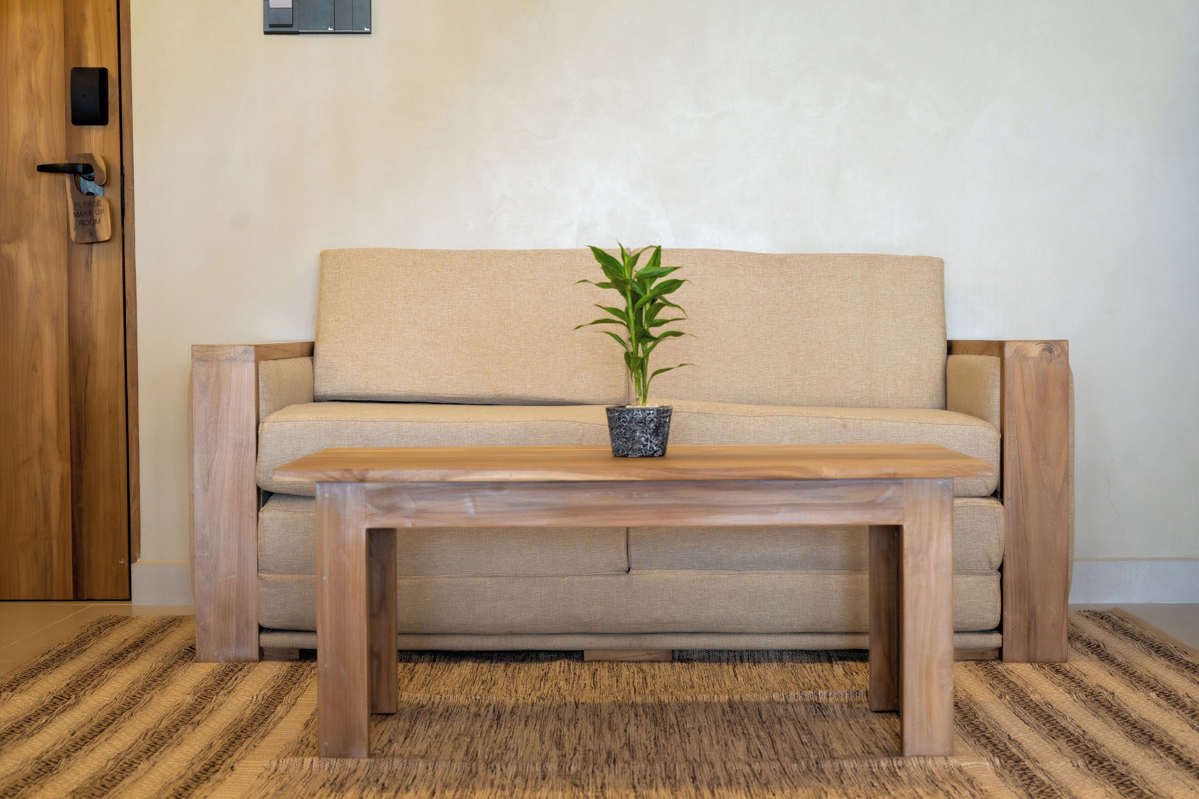 A wooden table with a potted plant in front of a beige sofa.