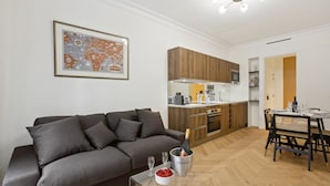 Un apartamento moderno con sofá gris, armarios de cocina de madera, una mesa de comedor con sillas y un mapa enmarcado en la pared.