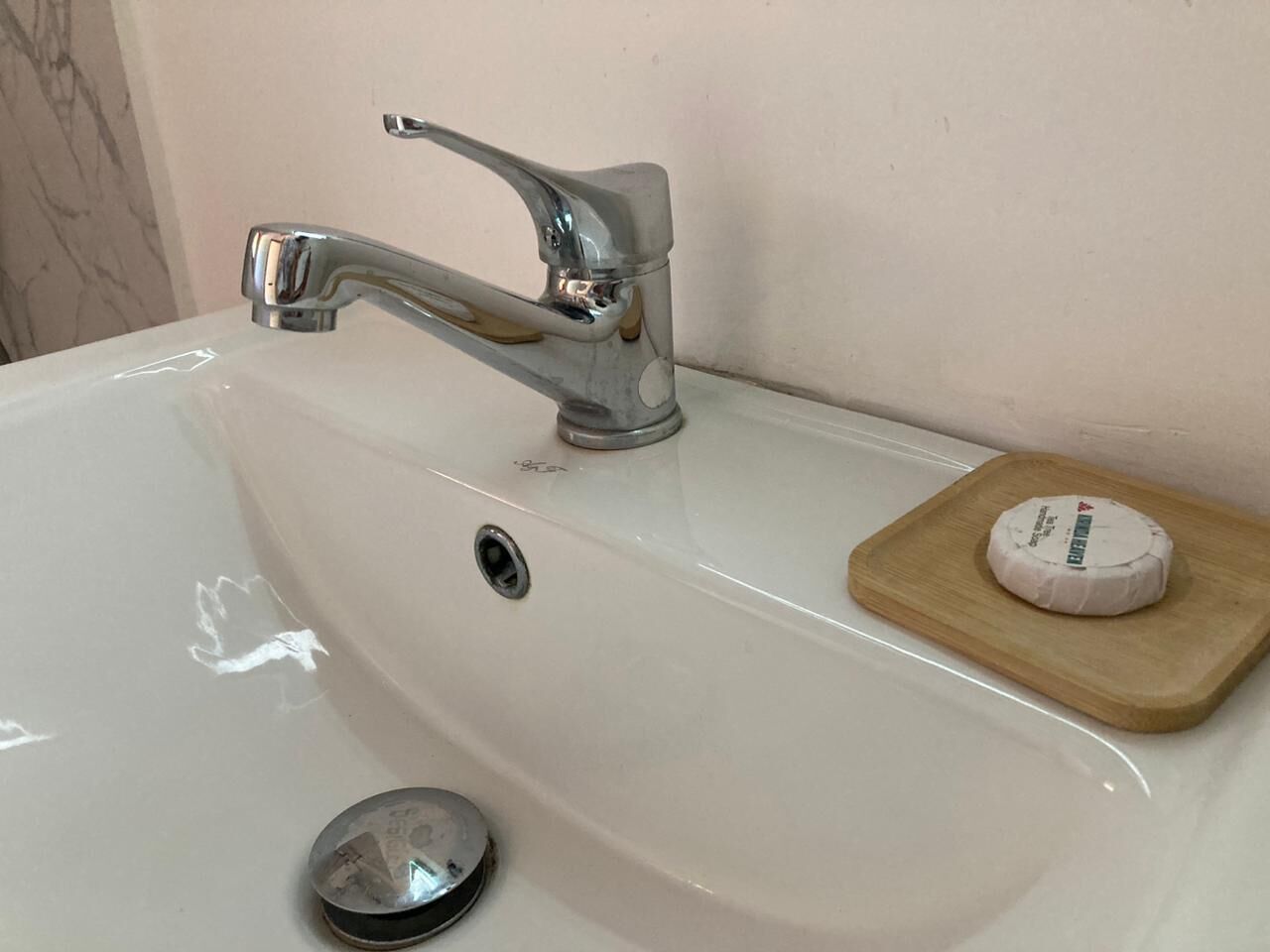 A bathroom sink with a chrome faucet, a drain, and a soap dish with a bar of soap.