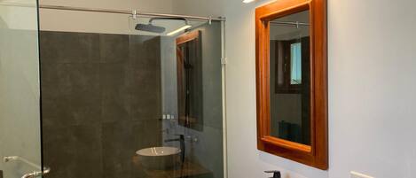 A modern bathroom with a glass-enclosed shower, a wooden vanity, and a large mirror.