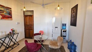 Un espacio habitable compacto con una mesa de comedor, dos sillas, un refrigerador y un dispensador de agua.