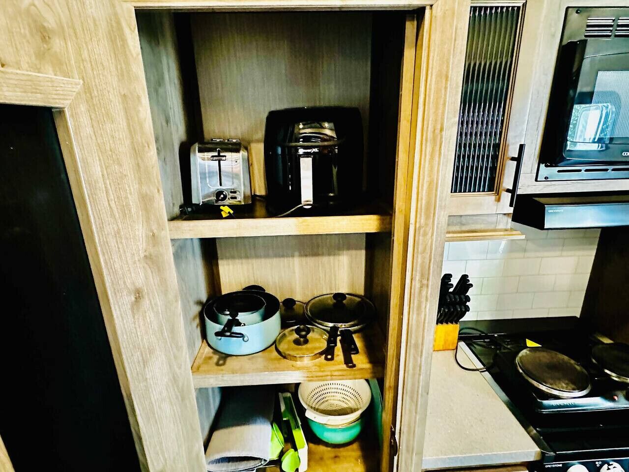 Cocina compacta con tostadora, cafetera, ollas y estufa.