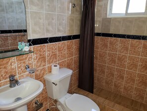 A bathroom with a sink, toilet, and a glass shelf with toiletries.