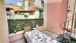 A small outdoor patio with a table and chairs, a wicker chair, a lamp, and a metal chair. - Casa Lentisco: A bright and sunny apartment which faces the sun and the sea, with Free WI-FI. (Camerota)
