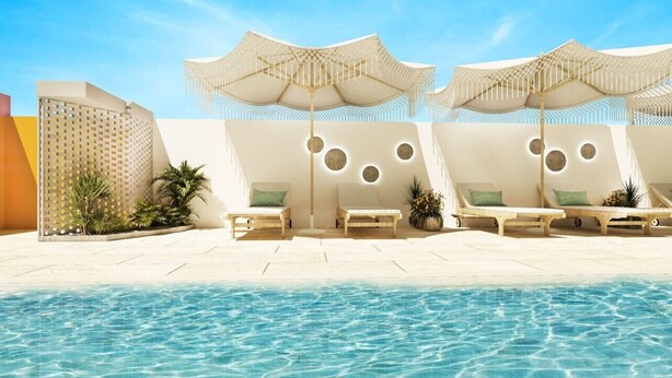Un espace aménagé au bord de la piscine, avec des chaises longues, des parasols et une piscine à l’eau d’un bleu limpide.