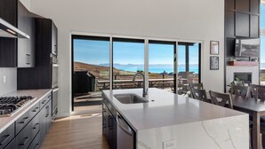 Eine moderne Küche mit einer großen Kochinsel, integrierten Geräten und Blick auf eine reizvolle Landschaft durch große Fenster.