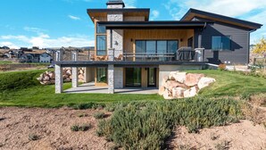 Ein modernes, zweistöckiges Haus mit Naturstein-Fassade, großen Fenstern und einer überdachten Terrasse.
