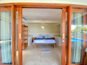 Une chambre à coucher avec un lit, une armoire en bois et une vue à travers une porte vitrée.