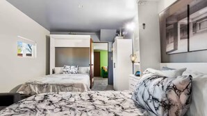 Une chambre d’hôtel avec deux lits, une armoire, un bureau et un tableau au mur.