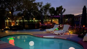 Une piscine équipée de chaises longues et d’un éclairage décoratif.