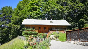 A wooden cabin with a gravel driveway, surrounded by lush greenery and a white fence. - Holiday Home 'Ferienhaus-Bregenzerwald' with Mountain View, Private Terrace and Wi-Fi (Bizau)