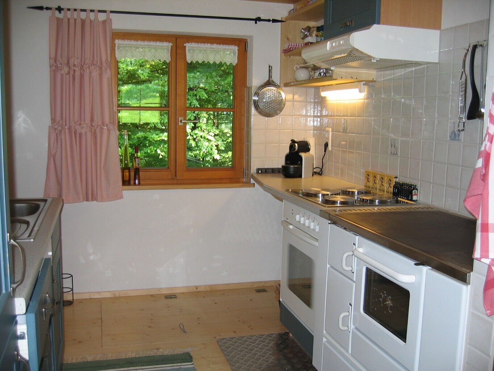 A kitchen with a window, a stove, an oven, and a sink.