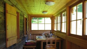 A cabin interior with a wooden table, chairs, a bench, a window, and a ceiling light fixture. - Holiday Home 'Ferienhaus-Bregenzerwald' with Mountain View, Private Terrace and Wi-Fi (Bizau)