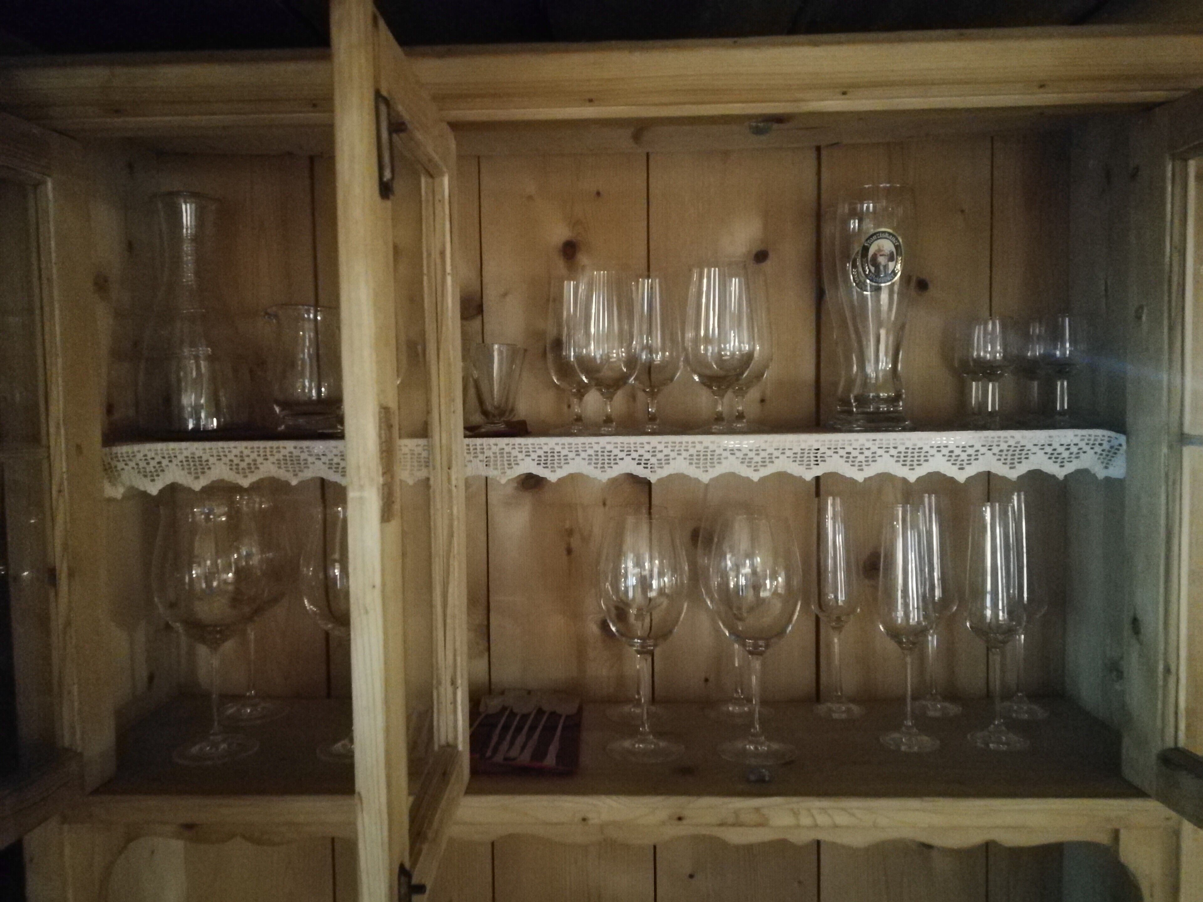 A wooden cabinet with shelves holding various glassware.