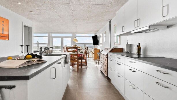 Cocina moderna con una isla central, muebles blancos y un amplio ventanal con vistas.