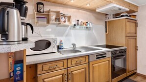 Een kleine keuken met een magnetron, waterkoker, spoelbak en oven.