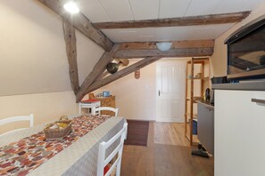 Une cuisine de taille réduite avec un plafond en bois, un coin repas comprenant une table et des chaises, et une porte blanche donnant sur une autre pièce.