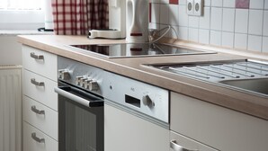 Eine Küche mit Einbauofen, Kaffeemaschine und Wasserkocher auf der Arbeitsplatte.