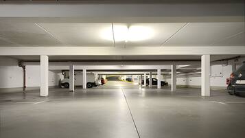 En indendørs parkeringskælder med hvide søjler, beton gulve og en midterste gang.