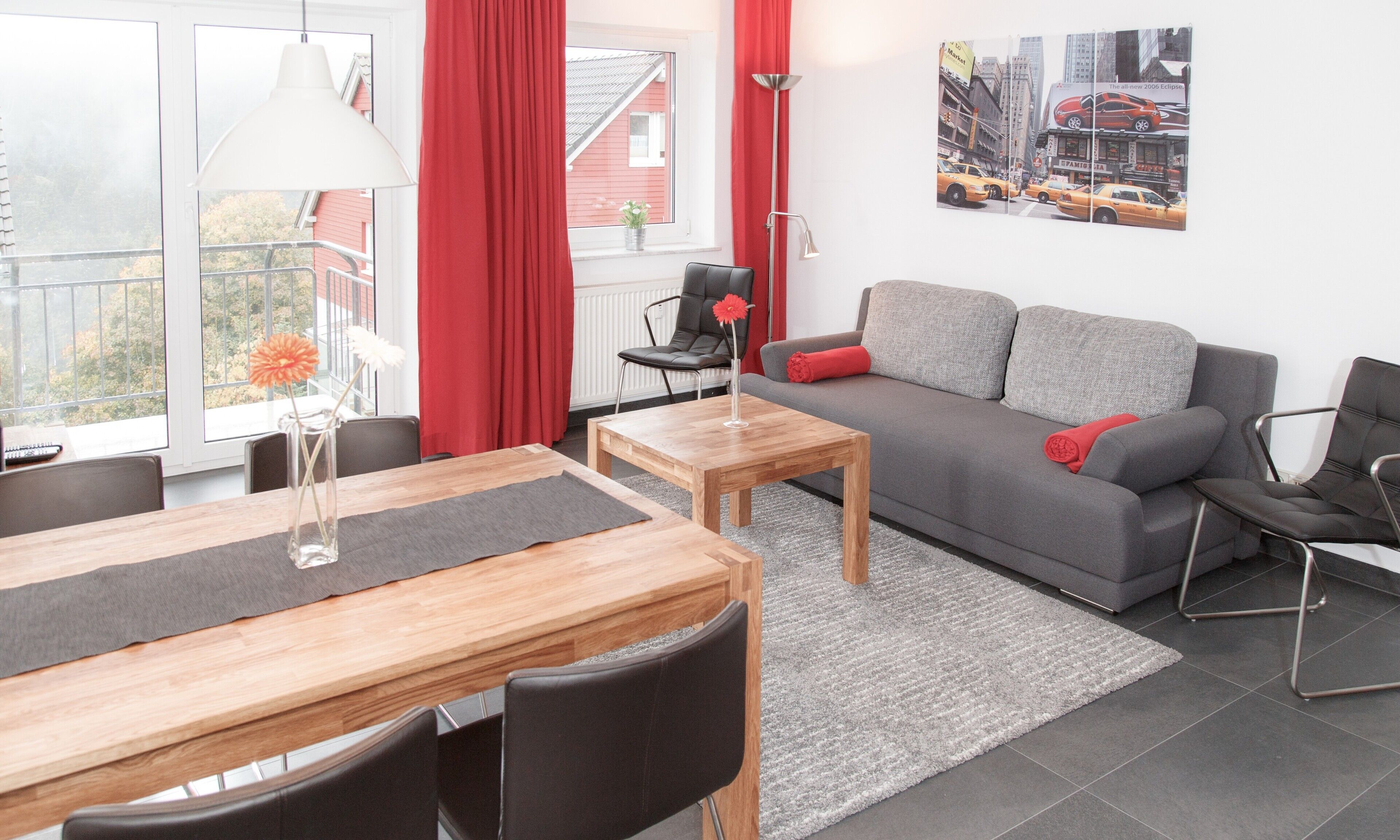 Un salon moderne avec un canapé gris, une table basse en bois et un coin repas comprenant une table et des chaises.