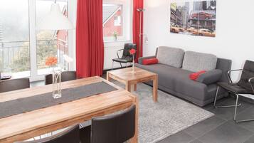 Un salon moderne avec un canapé gris, une table basse en bois et un coin repas comprenant une table et des chaises.
