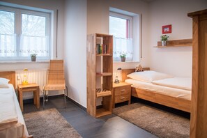 Une pièce comprenant un lit, une chaise, une bibliothèque en bois, un bureau et une fenêtre avec des rideaux.