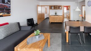 A modern living room with a sofa, coffee table, and dining area with chairs. - Apartment 'Ferienwohnung Tannenblick 3-4' with Mountain View, Balcony and Wi-Fi (Oberhof)